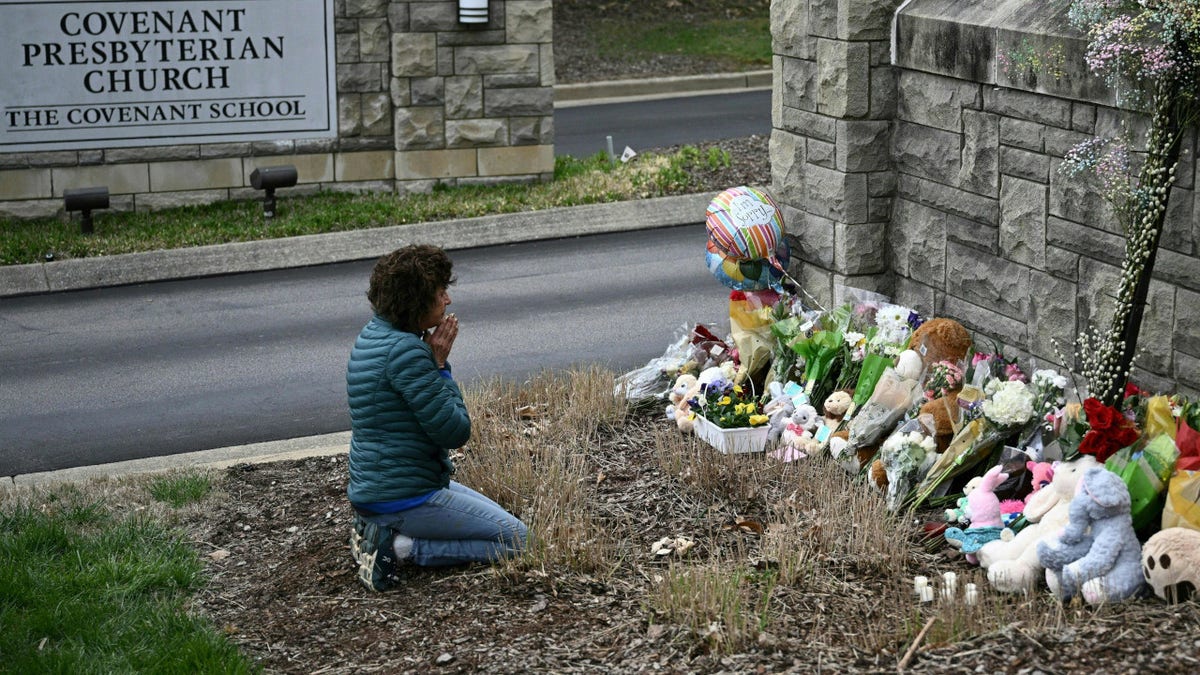 Kneeling woman prays at a makeshift memorial