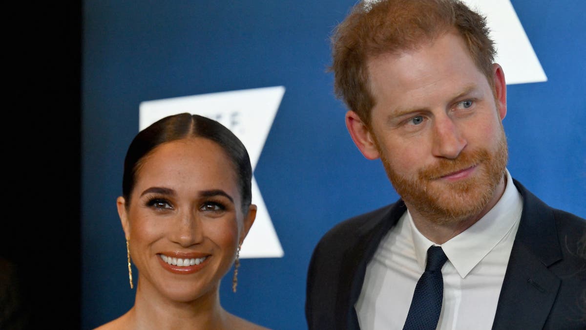 Meghan Markle and Prince Harry pose together for a photo at an event.