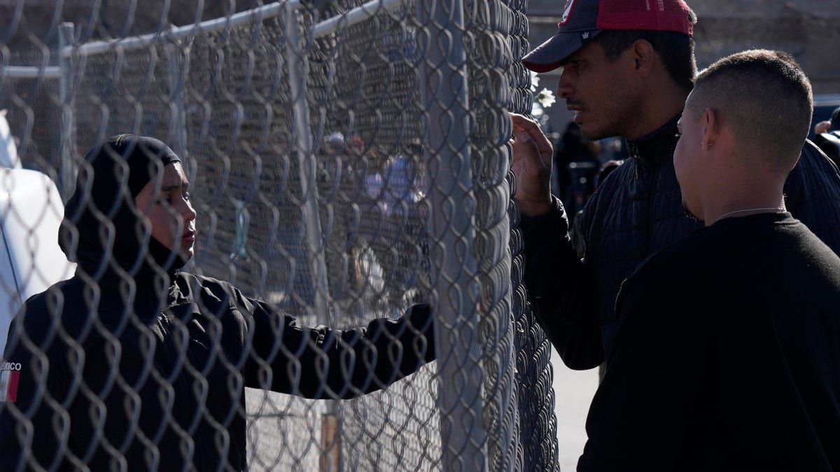 Migrants, right, as a member of the Mexican National Guard if there is any new information available regarding the victims of a fire at an immigration detention center that killed dozens, in Ciudad Juarez, Mexico, Tuesday, March 28, 2023.