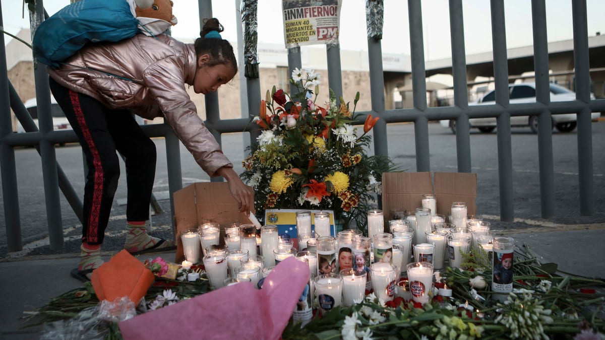A girl lights candle during a vigil for the victims of a fire at an immigration detention center that killed dozens in Ciudad Juarez, Mexico, Tuesday, March 28, 2023.