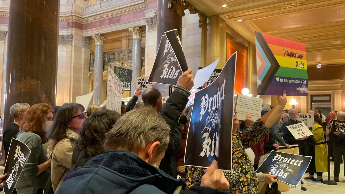 Protesters hold signs as they chant for and against a bill that would make Minnesota a trans refuge state