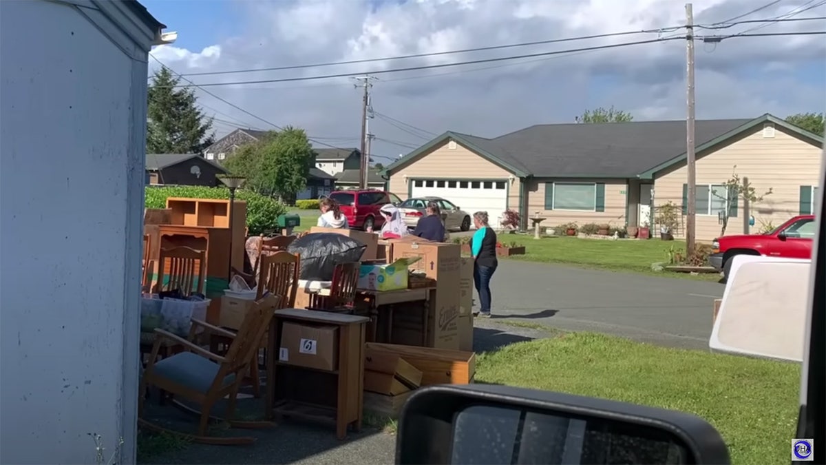 Accused squatters stand in a Northern California driveway near furniture and other belongings