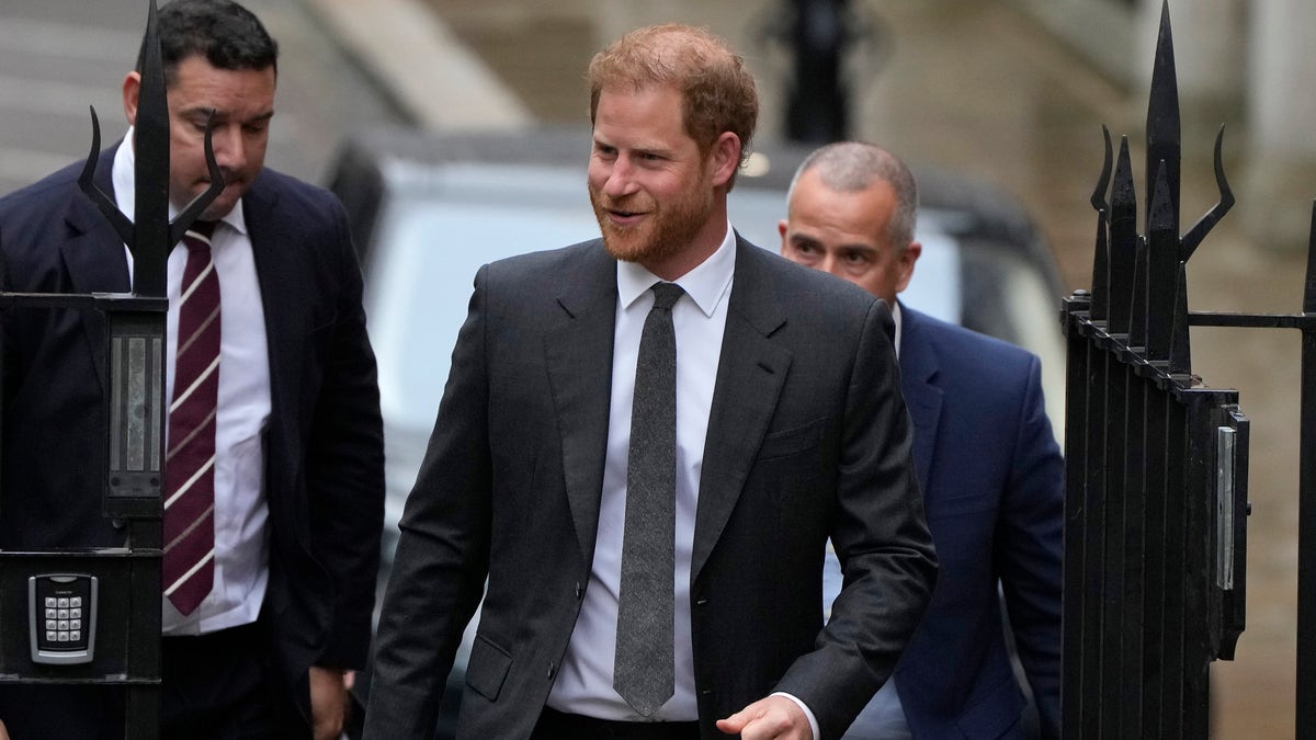Prince Harry smiles as he walks into court