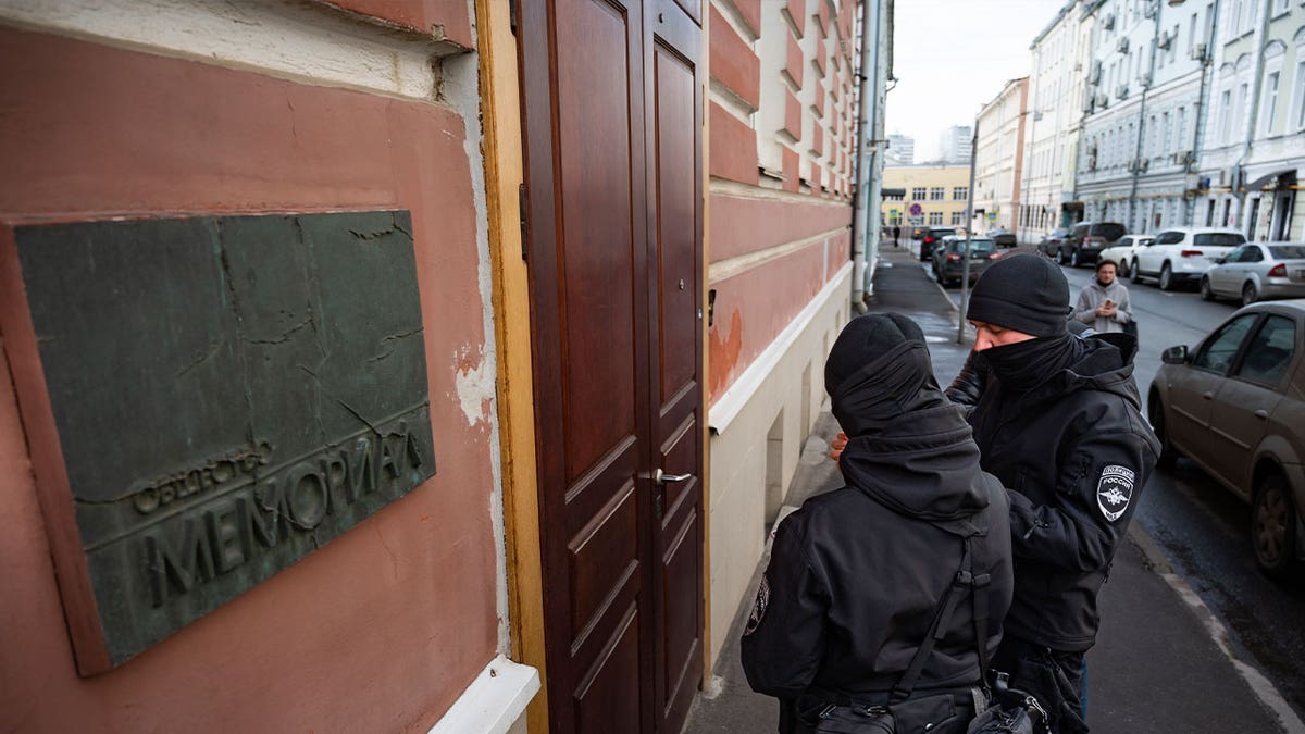 Two Russian police officers stand in front of the door of the Memorial office in Moscow, Russia, on March 21, 2023. Russian authorities raided homes and offices of human rights advocates and historians associated with the prominent rights group Memorial that won the Nobel Peace Prize last year. 