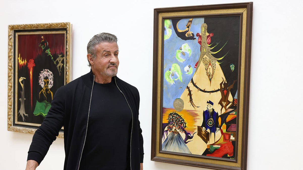 Sylvester Stallone looking at his paintings