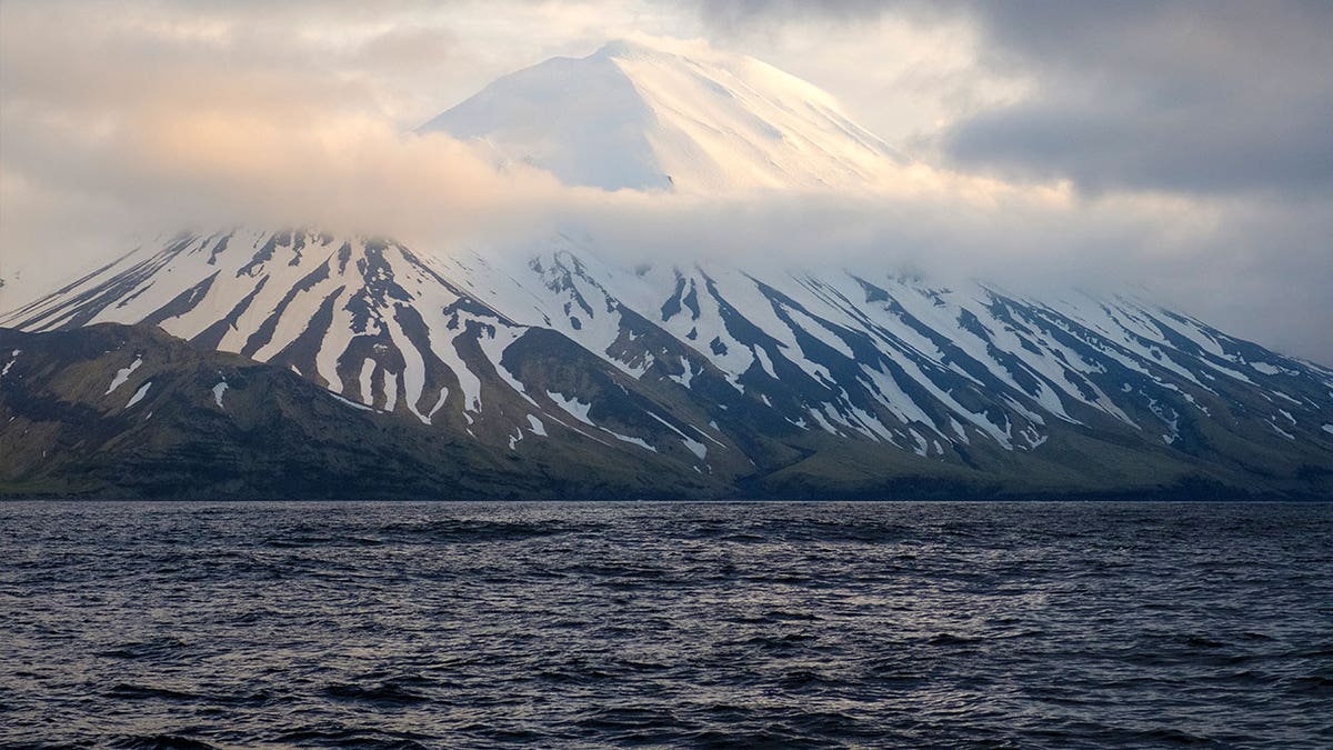 The Tanaga Volcano sits beneath clouds near Adak, Alaska, on May 23, 2021. A swarm of earthquakes occurring over the past few weeks has intensified at a remote Alaska volcano dormant for over a century.