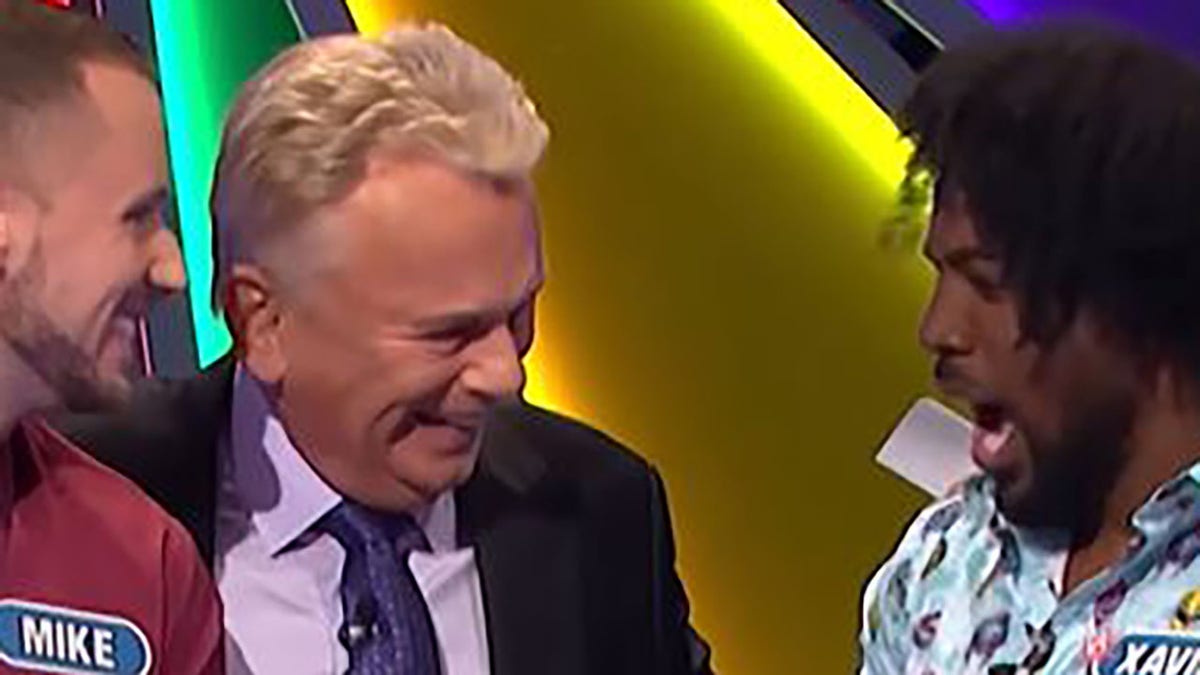 Pat Sajak laughing with contestant Xavier Woods