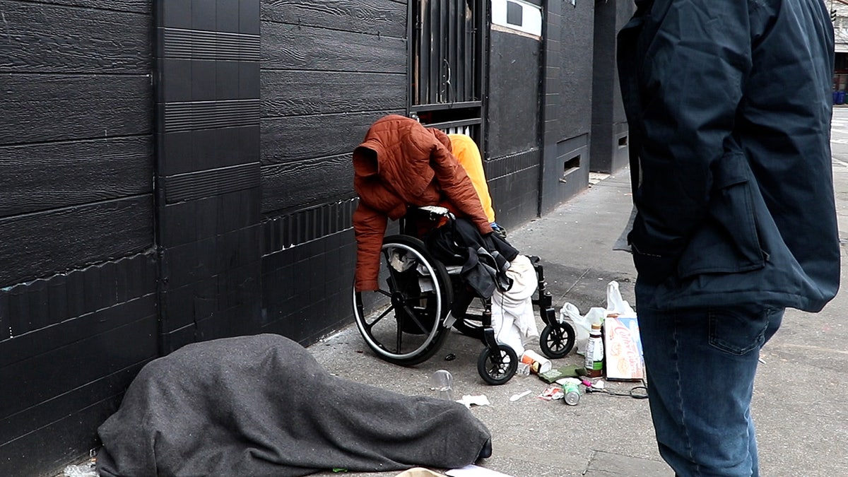 Man in wheelchair and woman sleeping on sidewalk in Portland, Oregon