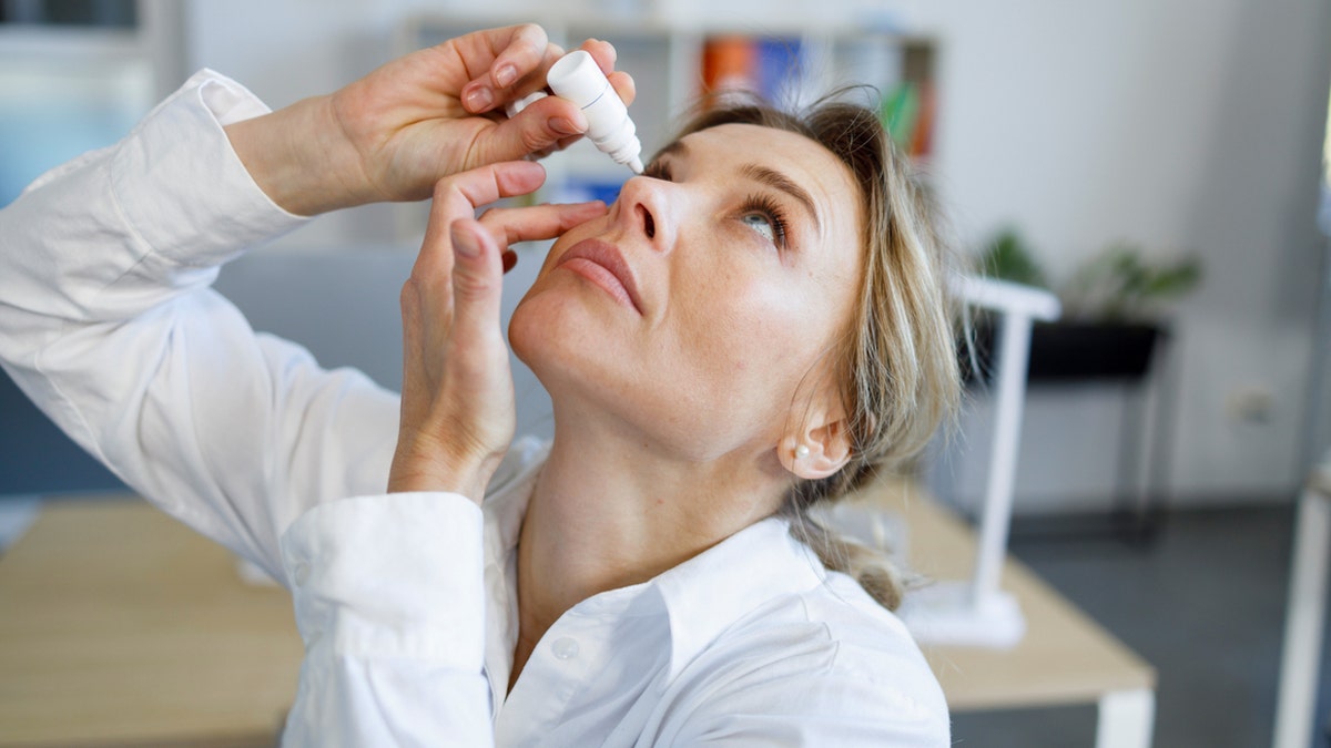 Woman putting in eye drops