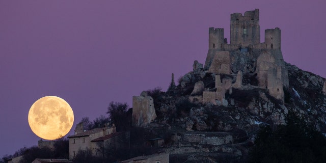 Une pleine lune se couche derrière le château et le village de Rocca Calascio (LAquila), Italie, le 7 mars 2023. La pleine lune de mars est également connue sous le nom de lune de ver, car elle coïncide avec la période de l'année où les vers de terre commencent à émerger de le sol.