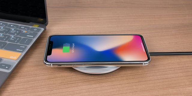 An iPhone charging on a desk. Apple iOS 16.1 has a new update with a clean energy feature.