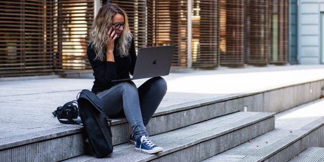 Wanita di laptop sambil duduk di tangga