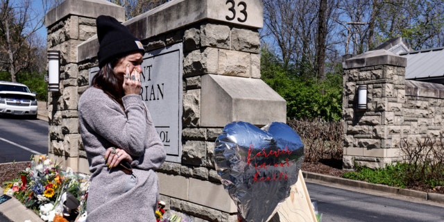 A woman wipes away tears as she visits a memorial at the entrance to The Covenant School on March 29, 2023, in Nashville.