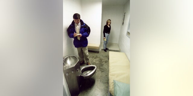 Reporters Scott McGrew and Amy Donaldson view the cell where John Albert Taylor spent his final day before his firing squad execution at the Unita State Penitentiary in Utah in 1996. Taylor, who chose to die by a firing squad of five men instead of a lethal injection, was the first to die by firing squad since Gary Gilmore's execution in 1977.
