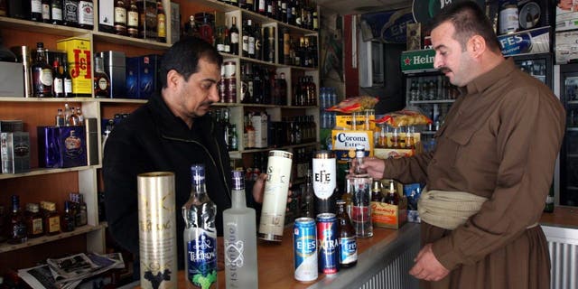 A shopkeeper shows a selection of Turkish alcoholic beverages to a Kurdish man at a shop in Arbil, north of Baghdad December 8, 2010.