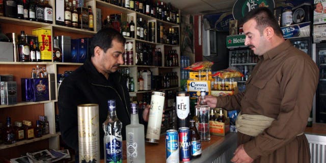 A shopkeeper shows a selection of Turkish alcoholic beverages to a Kurdish man at a shop in Arbil, north of Baghdad December 8, 2010.