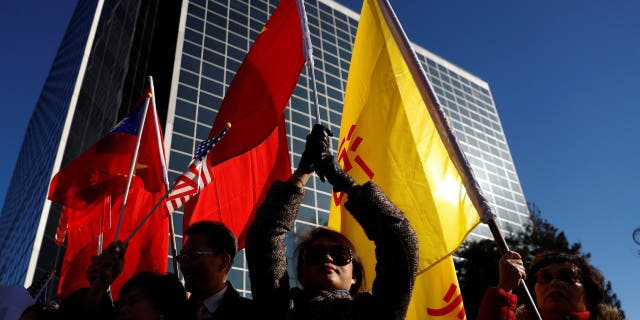 Protesters hold the flags of China and Taiwan as Taiwanese President Tsai Ing-wen pauses after his visit to Latin America in January 2017.