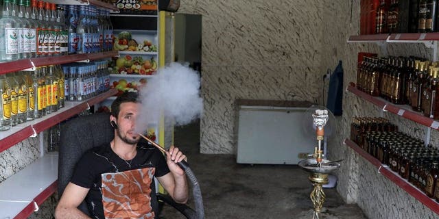 Liquor store owner Steve Ibrahim smokes in the city of Qaraqosh, south of Mosul, Iraq April 13, 2017.