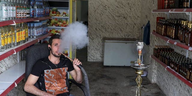 Steve Ibrahim, an alcohol shop owner, smokes in the town of Qaraqosh, south of Mosul, Iraq, April 13, 2017.