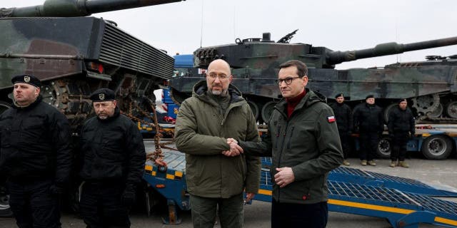 Ukrainian Prime Minister Denys Shmyhal and Polish Prime Minister Mateusz Morawiecki shake hands during the delivery of tanks to Ukraine, Feb. 24, 2023.
