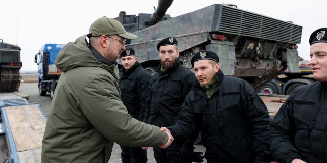Ukrainian Prime Minister Denys Shmyhal greets Polish service members delivering Leopard 2 tanks on the first anniversary of Russia's attack, in Ukraine on Feb. 24, 2023.