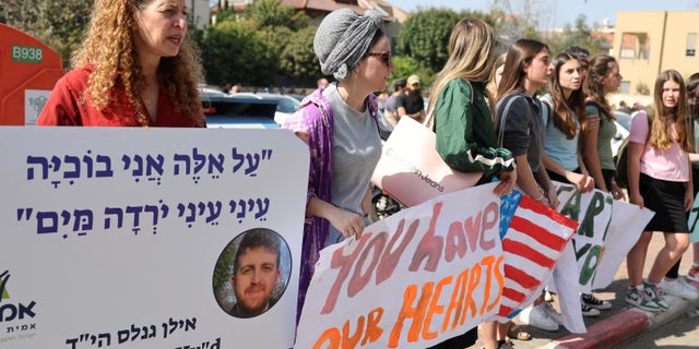 People hold placards as they mourn Elan Ganeles, a dual U.S.-Israeli citizen killed in a terrorist attack while he was driving near the West Bank city of Jericho by suspected terrorists, during his funeral, outside the cemetery, in Raanana, Israel, March 1, 2023. REUTERS/Nir Elias