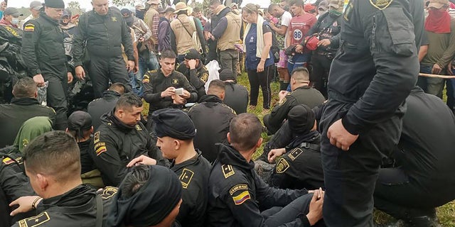 La policía se sienta cerca de funcionarios de la Defensoría del Pueblo de Colombia mientras hablan con los manifestantes en San Vicente del Caguán, Colombia, el 2 de marzo de 2023. 