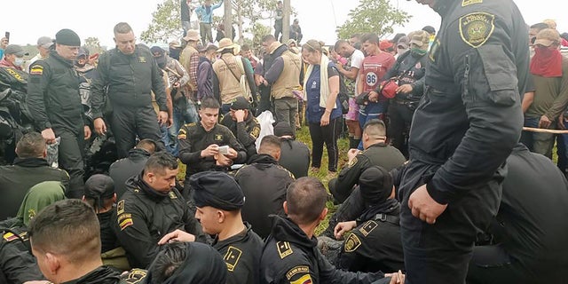 Police sit near officials from Colombia's human rights ombudsman while they speak with demonstrators in San Vicente del Caguan, Colombia, March 2, 2023. 