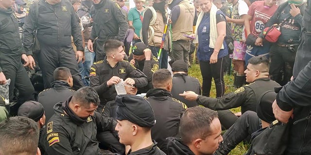 Police sit while officials from Colombia's human rights ombudsman speak with demonstrators who, according to authorities, belong to rural and Indigenous communities and are demanding that oil company Emerald Energy build roads in San Vicente del Caguan, Colombia, March 2, 2023. 