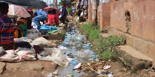 Vendors selling clothes and other merchandise in the city of Lilongwe, Malawi. Behind them is polluted water. Poor drainage facilities are a problem in the cholera infested country.