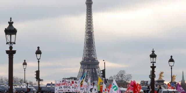 Demonstrators holds banners as they gather on the place de la Concorde near the National Assembly, with the Eiffel tower in the background, to protest after French Prime Minister Elisabeth Borne delivered a speech to announce the use of the article 49.3, a special clause in the French Constitution, to push the pensions reform bill through the lower house of parliament without a vote by lawmakers, in Paris, France, March 16, 2023.   