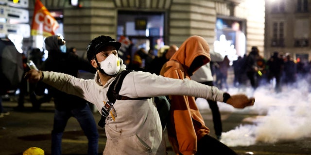 A demonstrator trows a projectile amid clashes during a protest after French Prime Minister Elisabeth Borne used the article 49.3, a special clause in the French Constitution, to push the pensions reform bill through the National Assembly without a vote by lawmakers, in Nantes, France, March 16, 2023.  