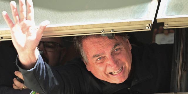 Former Brazilian President Jair Bolsonaro waves to supporters at Brasilia International Airport on March 30, 2023, as he returns from self-imposed exile in Florida.