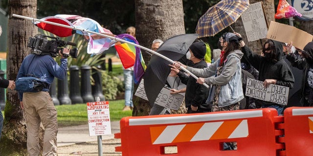 A protester swings a pole and its attached flags at TV news photographer Ken Day as demonstrators moved toward the Capitol to protest a ''Detransition Awareness Day'' event on March 10.