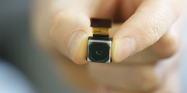 The person holds a small camera.