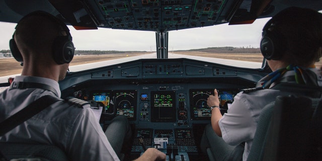 Pilots sit in cockpit with headsets on