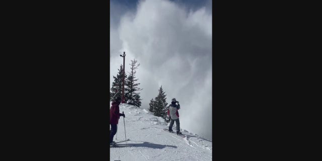 Giant snow clouds approach the hills where the skiers are standing