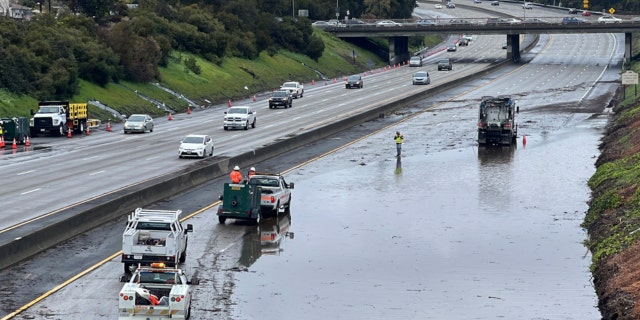 Caltrans crews work by a flooded section of Interstate 580 in Oakland, Calif., Friday, March 10, 2023. A new atmospheric river has brought heavy rain and thunderstorms to California, bringing flood threats and disrupting travel.