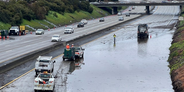 Caltrans crews work by a flooded section of Interstate 580 in Oakland, Calif., Friday, March 10, 2023. A new atmospheric river has brought heavy rain and thunderstorms to California, bringing flood threats and disrupting travel.