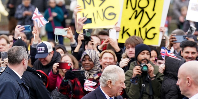 Demonstrators hold placards reading "Not My King" as Britain's King Charles III (C) meets well-wishers upon arriving at the Church of Christ the Cornerstone in Milton Keynes, north of London on February 16, 2023, to attend a reception to mark Milton Keynes' new status as a city. 