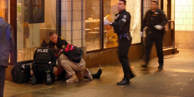 Police officers attend to one of several shooting victims outside McDonald's on Third Avenue in Seattle on Jan. 22, 2020. The Seattle Times and Las Vegas Review-Journal report that Marquise Tolbert and William Tolliver were booked into jail in Clark County, Nevada, according to jail records.