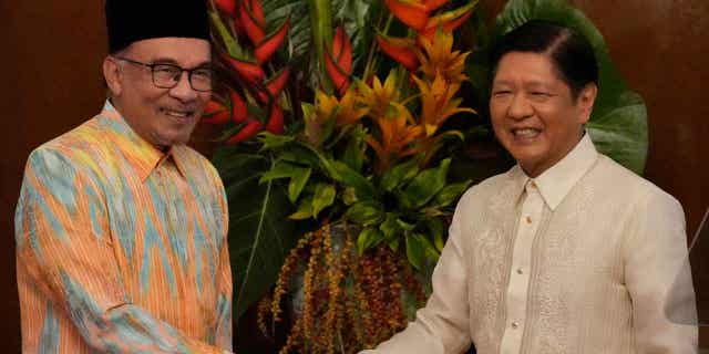 Philippine's president, right, shakes hands with Malaysia's prime minister after delivering their statements to the press in Manila, Philippines, on Mar. 1, 2023. Malaysia's prime minister claims over 200,000 migrants have entered his country from Burma.