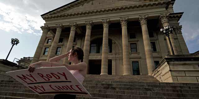 A woman from Topeka, Kansas, stands on the steps of the Kansas Statehouse during a rally to protest the Supreme Court's ruling on abortion on June 24, 2022. The state's Supreme Court is set to review two lawsuits regarding abortion laws in the state.
