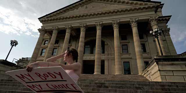 A protestor from Topeka stands on the steps of the Kansas Statehouse during a rally to protest the Supreme Court's ruling on abortion on June 24, 2022. Seven months after abortion rights were affirmed in the state, the GOP-controlled Legislatures proposed multiple anti-abortion laws.