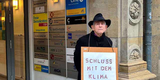 Father Reinhart Kraft of the poses with a protest poster in front of the headquarters of the German Liberal Party in Berlin, Germany, on March 3, 2023. 