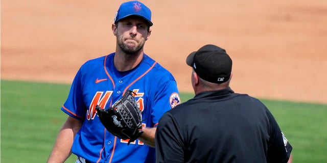 New York Mets starting pitcher Max Scherzer, left, talks with the home plate umpire during a spring training baseball game against the Washington Nationals, Friday, March 3, 2023, in Port St. Lucie, Fla.