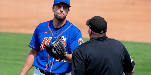 New York Mets starting pitcher Max Scherzer, left, talks with the home plate umpire during a spring training baseball game against the Washington Nationals, Friday, March 3, 2023, in Port St. Lucie, Fla.