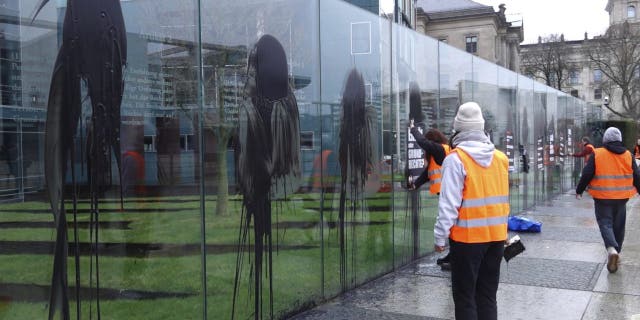 Climate activists of the "Last Generation" attend a protest at the Jakob-Kaiser-Building in Berlin Saturday, March 4, 2023. Climate activists on Saturday splashed a dark liquid over an artwork near the German parliament building engraved with key articles from the country's constitution, drawing condemnation from the speaker of parliament and other lawmakers.