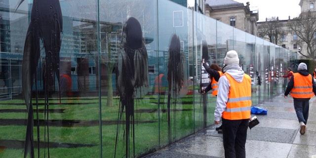 Climate activists of the "Last Generation" attend a protest at the Jakob-Kaiser-Building in Berlin, Germany, Saturday, March 4, 2023. Climate activists on Saturday splashed a dark liquid over an artwork near the German parliament building engraved with key articles from the country's constitution, drawing condemnation from the speaker of parliament and other lawmakers.