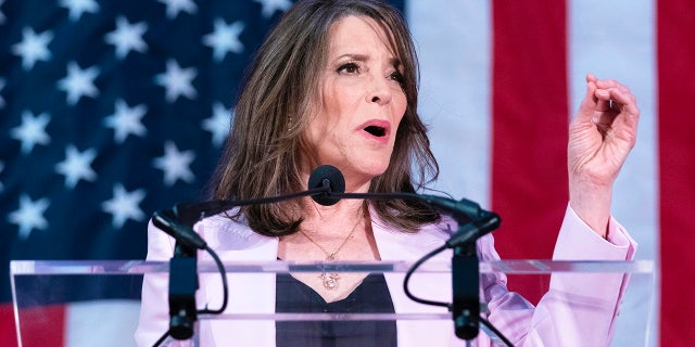 Marianne Williamson left hand raised at podium